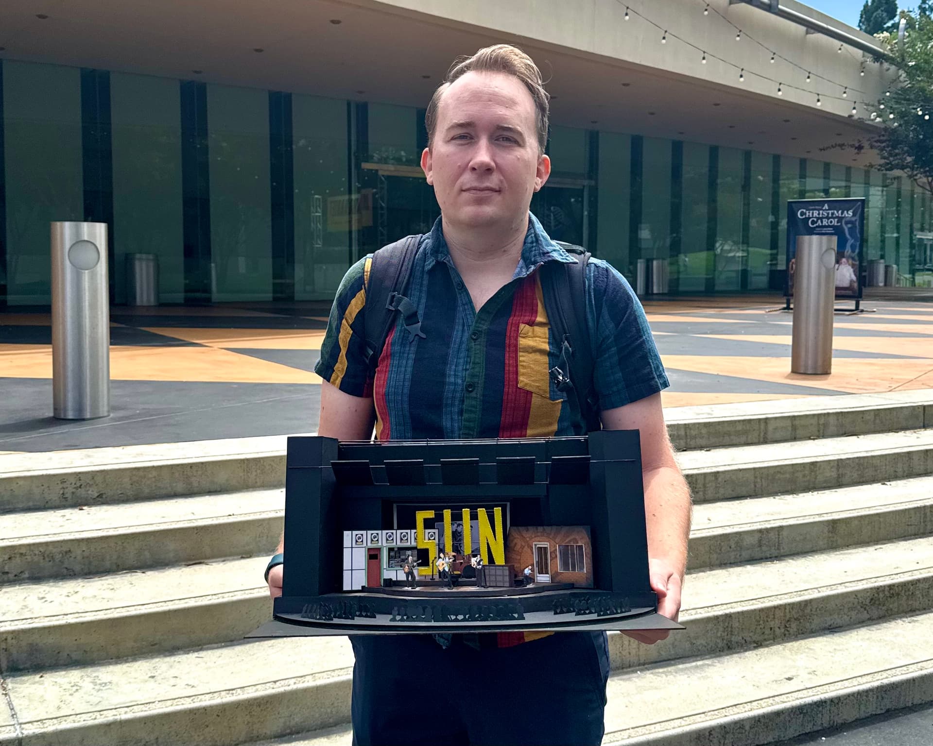 Brandon PT Davis at age 38 outside South Coast Repertory, holding a scenic model for a production design.