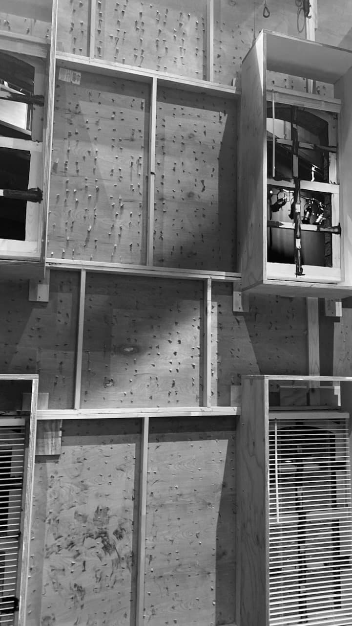 A black-and-white view of unfinished scenic wall units with window openings and textured plywood.