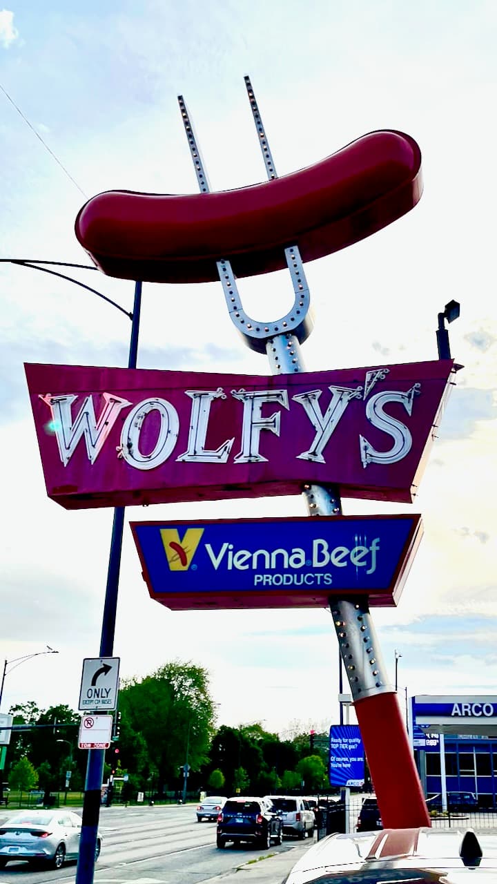 The Wolfy's Vienna Beef sign with a large red hot dog shape above the street.