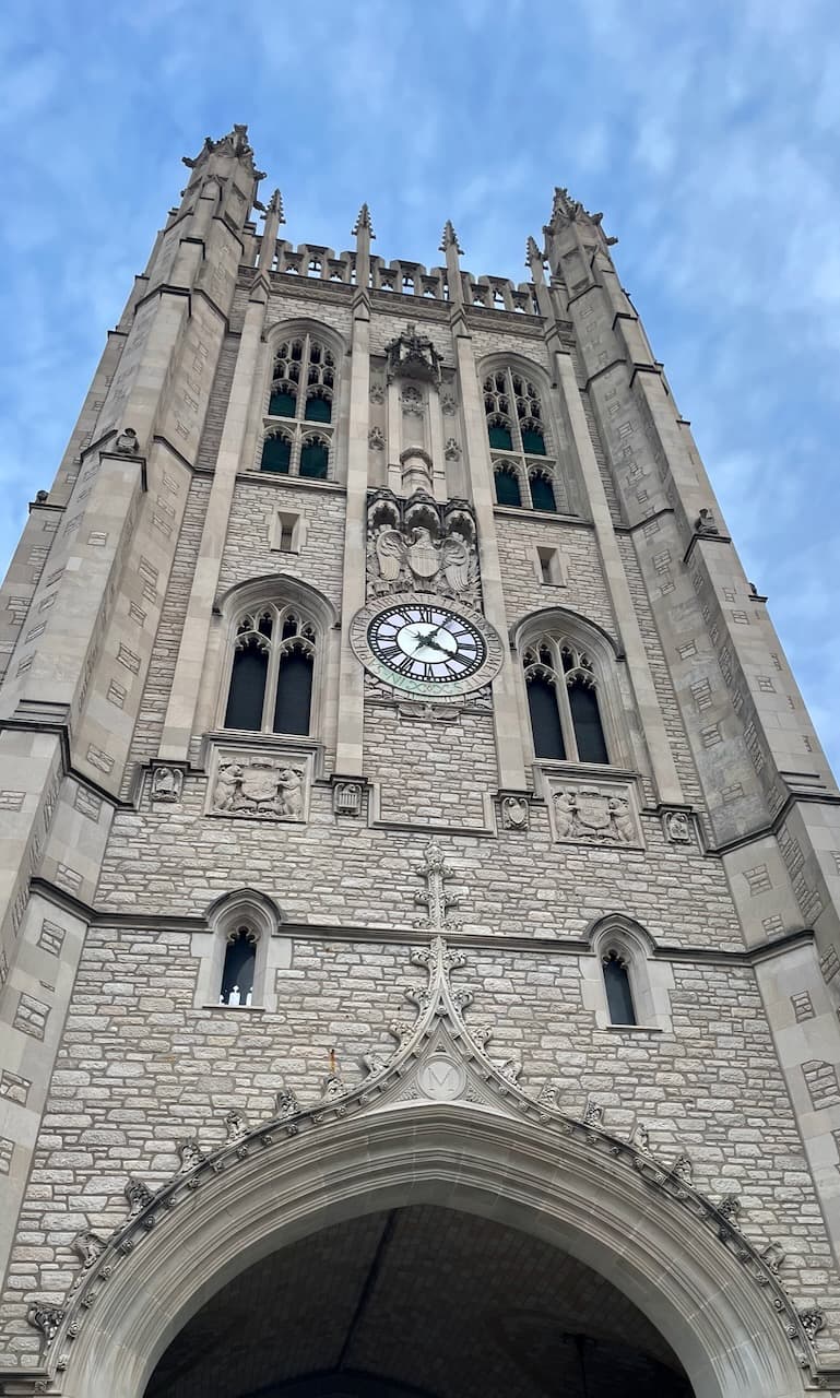 A University of Missouri stone clock tower photographed from below against a blue sky.