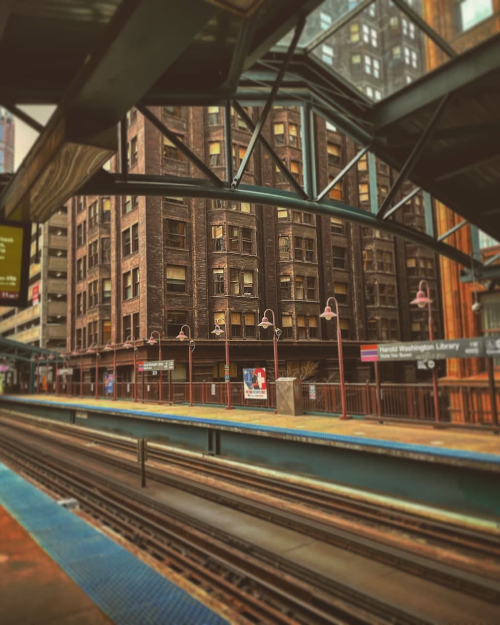 An elevated train platform with tracks, steel framing, and brick buildings beyond.