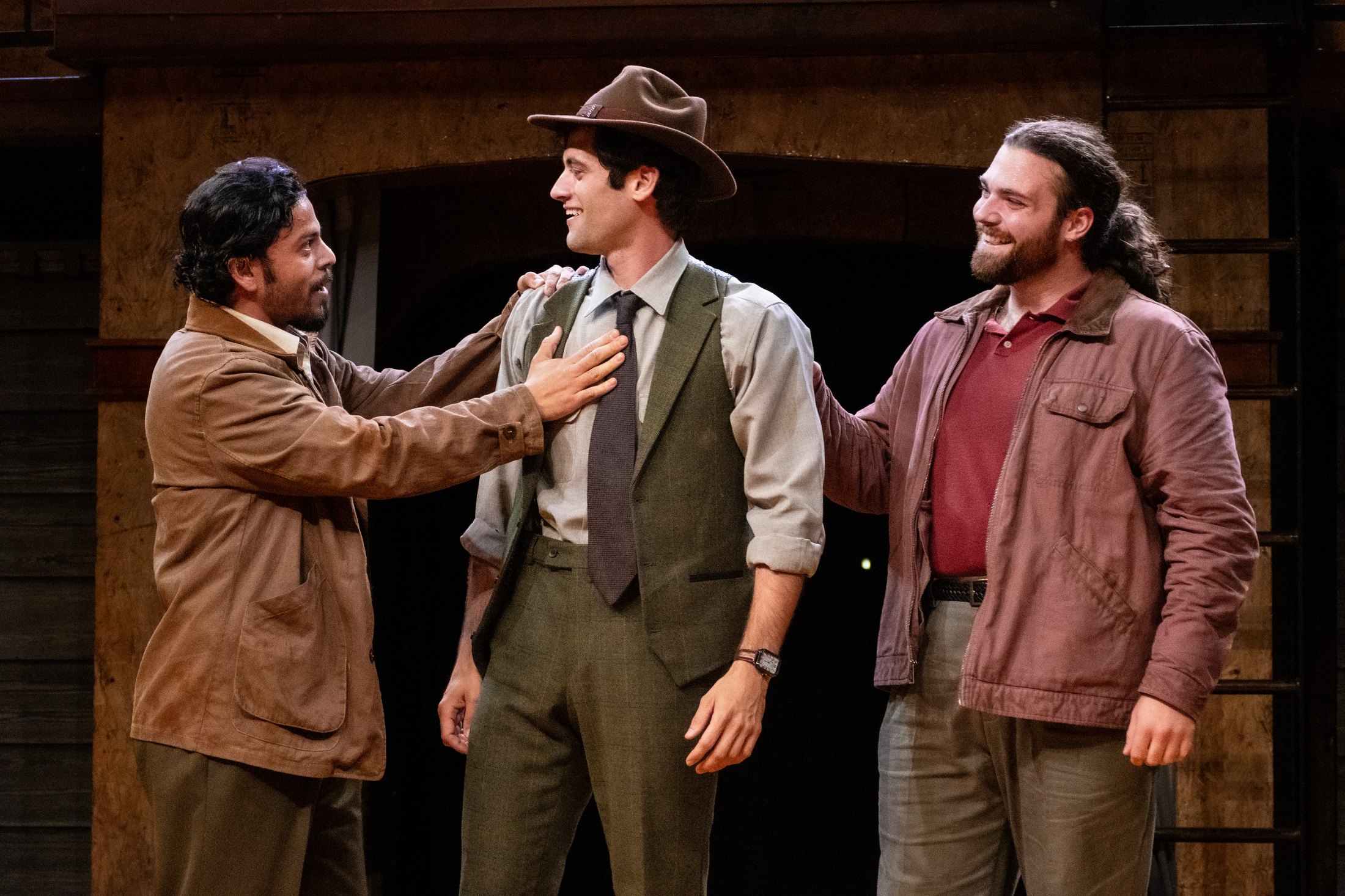 Three men gather beneath the warm timber walls of the scenic environment.