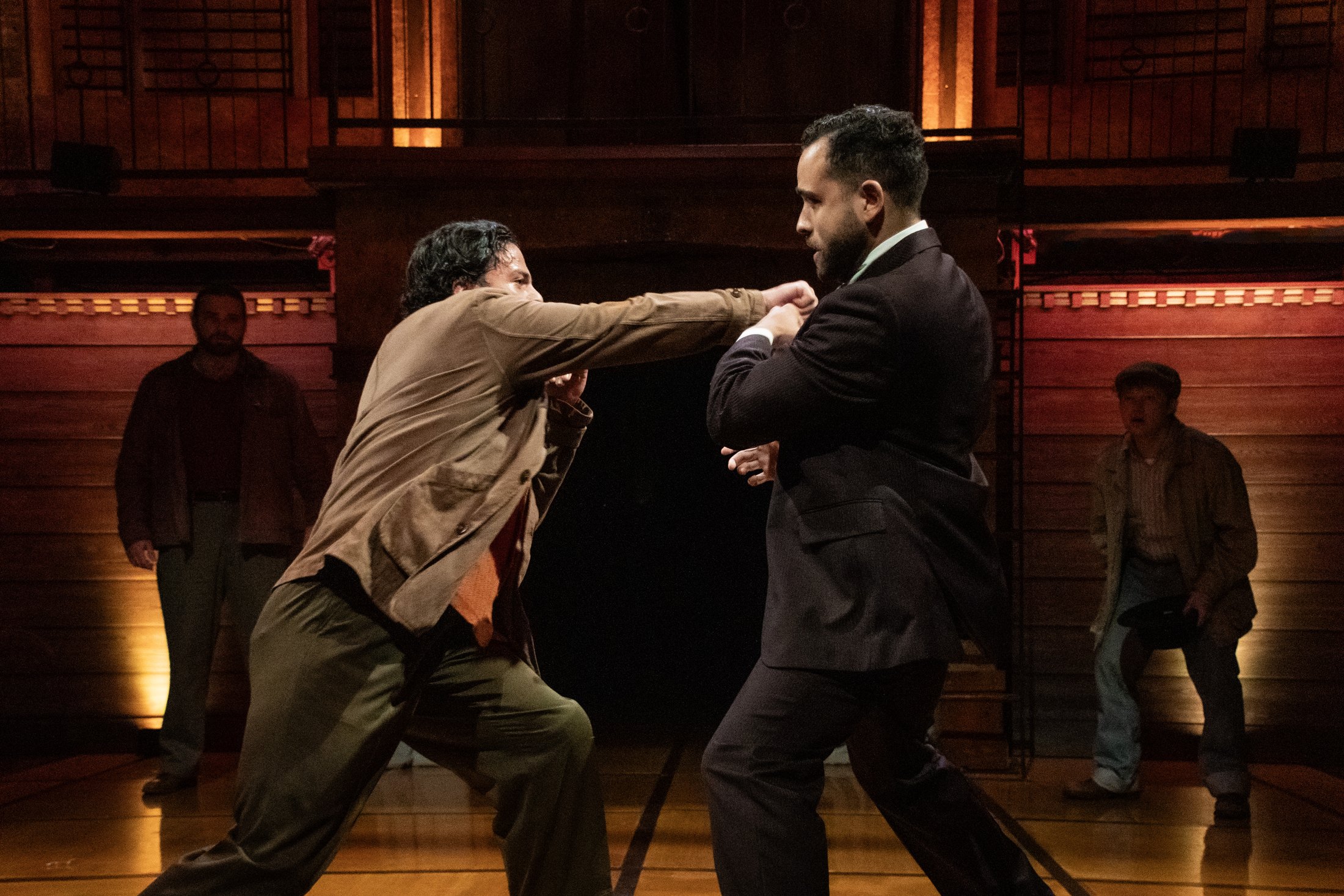 A confrontation crosses the open floor beneath the upper gallery.