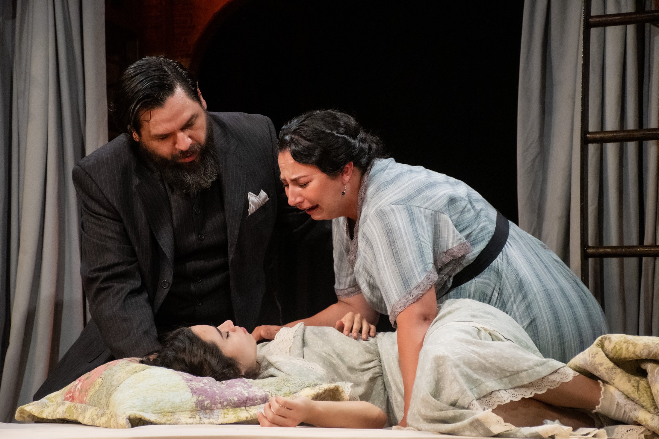 The Nurse and Friar Laurence gather around Juliet in the spare interior.