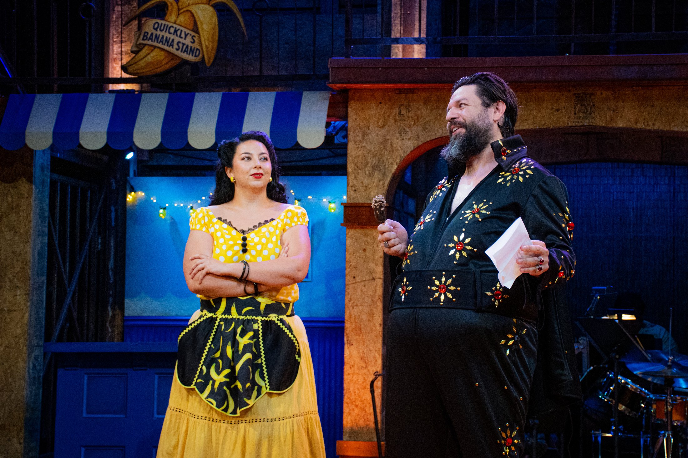 Two characters converse within the colorful 1950s Southern California setting.