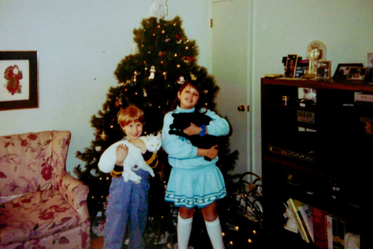 Brandon PT Davis with his sister Megan at Christmas in the 1990s, holding cats Silvia and Christina.