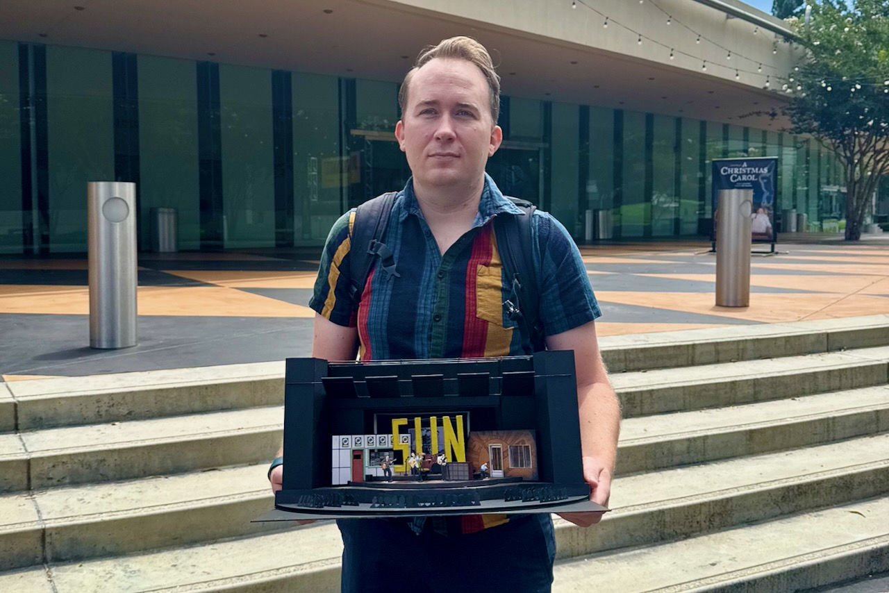 Brandon PT Davis holding a scenic model during a design presentation at South Coast Repertory.