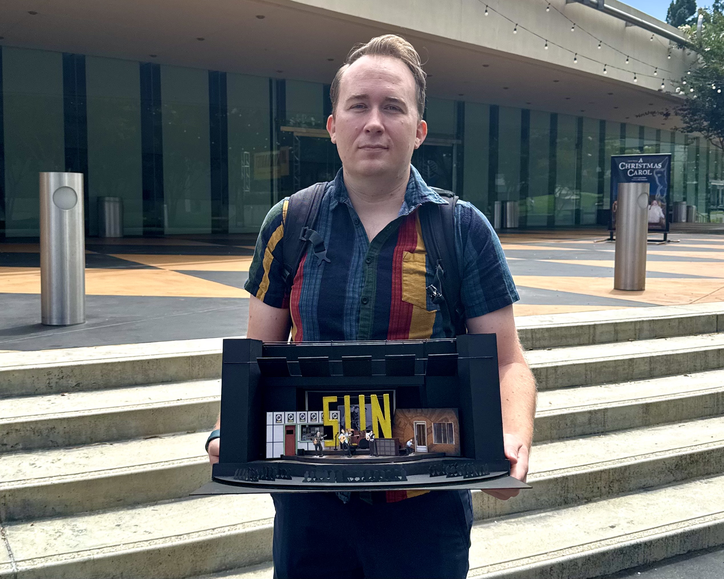 Brandon PT Davis at age 38 outside South Coast Repertory, holding a scenic model for a production design.
