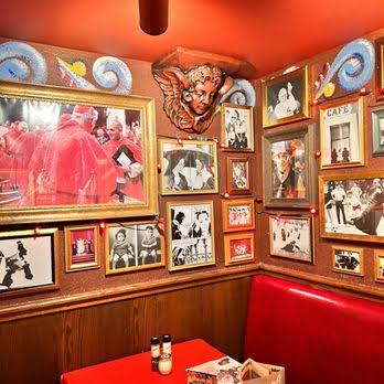 Wall of framed photographs and dense decorative imagery at Buca di Beppo.