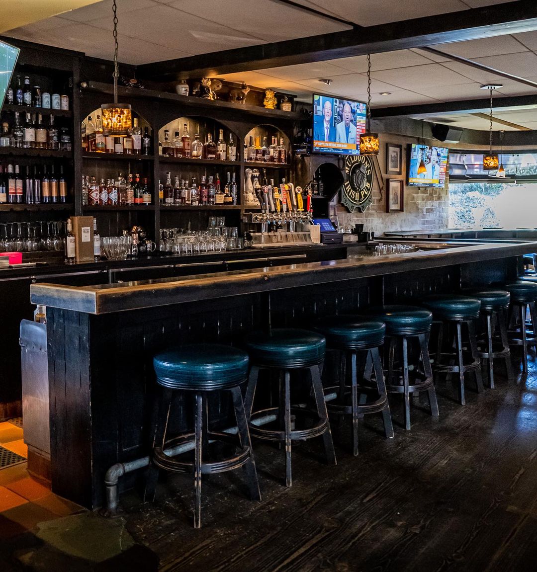Bar area at Muldoon's Irish Pub with dark wood, pub seating, and social lighting.