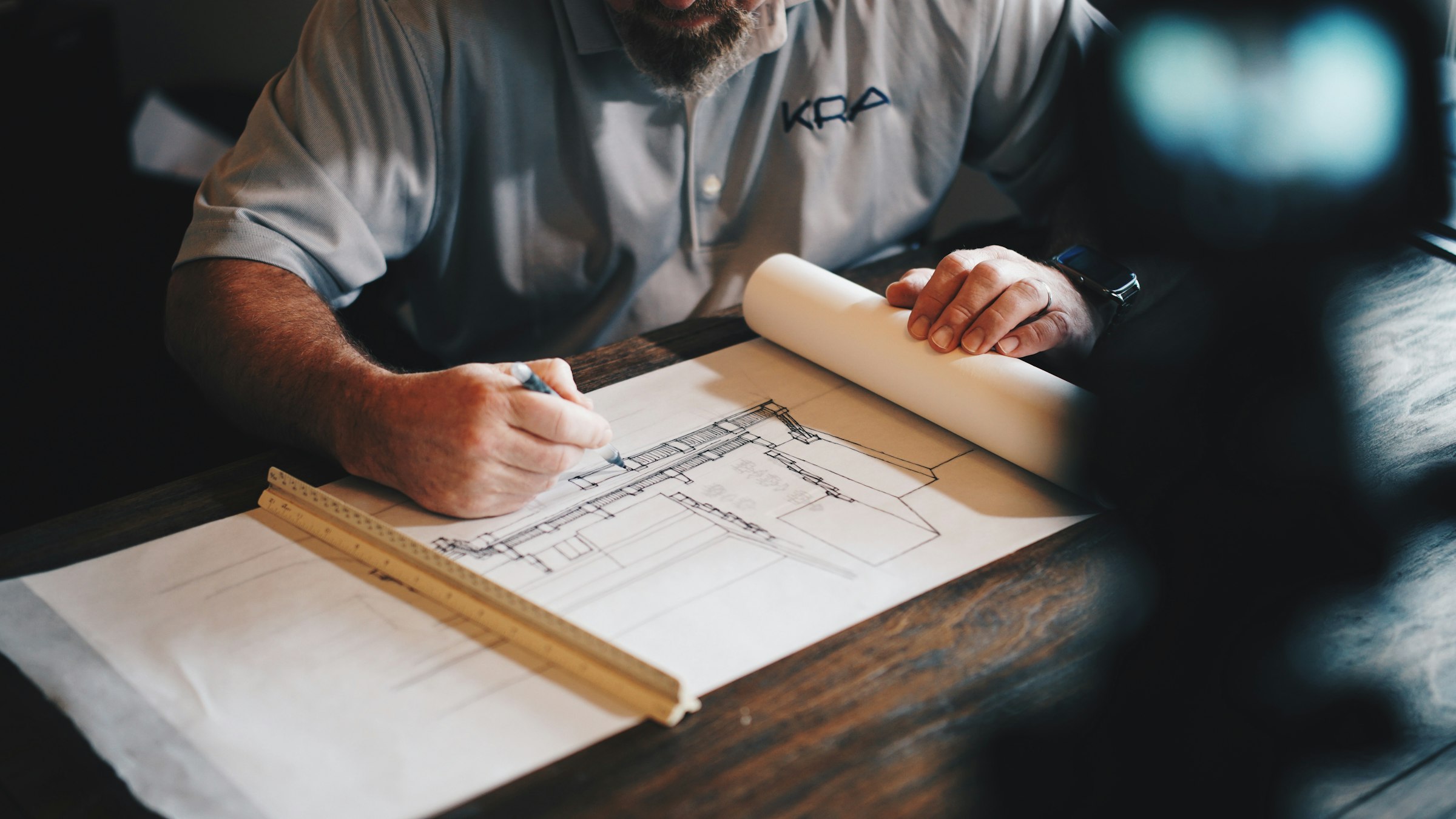 Architectural drafting table with plans, drawing tools, and material references.